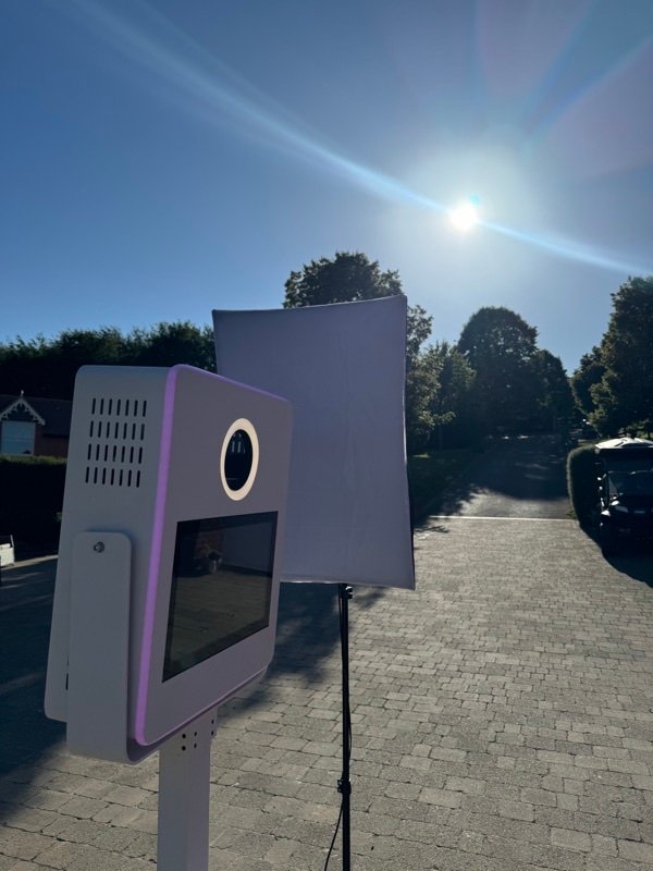 The PhotoGenieBooths booth and backdrop set up outdoors on a sunny driveway