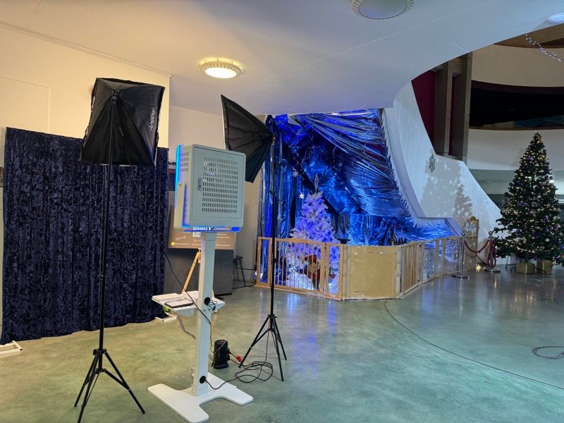 PhotoGenieBooths photo booth set up at a Christmas party with a blue metallic backdrop